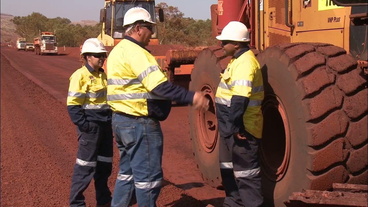 3 people in high visibility standing in front of a tractor